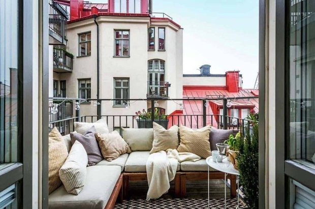 Как сделать пространство открытого балкона более приватным? Помогут диван или софа, развернутые спинкой на улицу. А на перила повесьте кашпо с растениями.