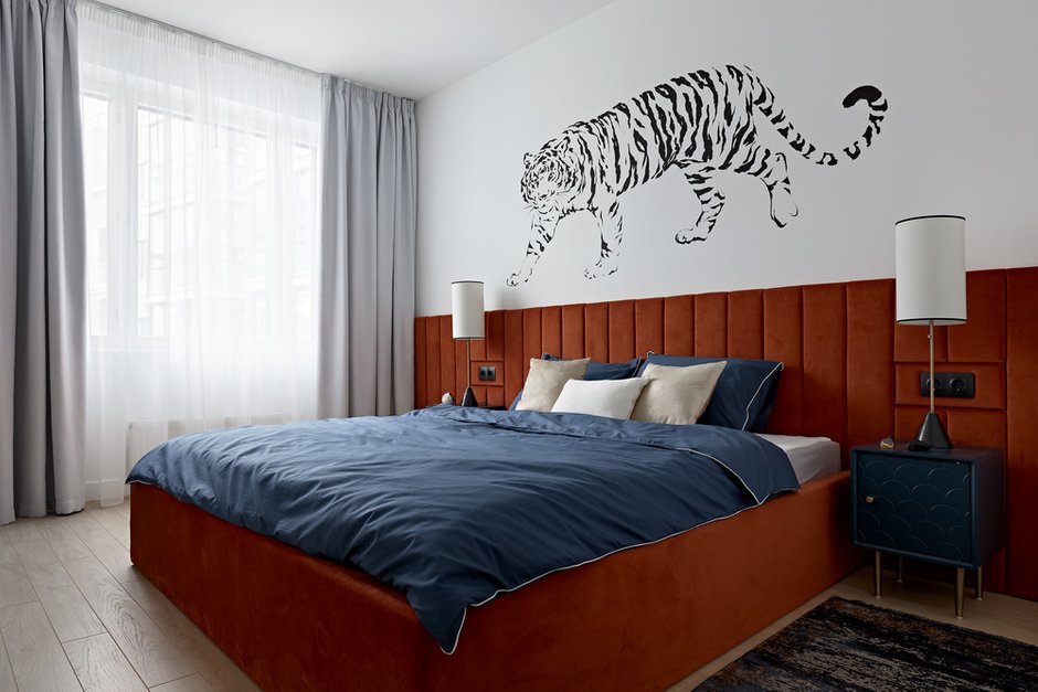 Мягкое изголовье кровати цвета тигровой шкуры создает уют, несмотря на яркость.