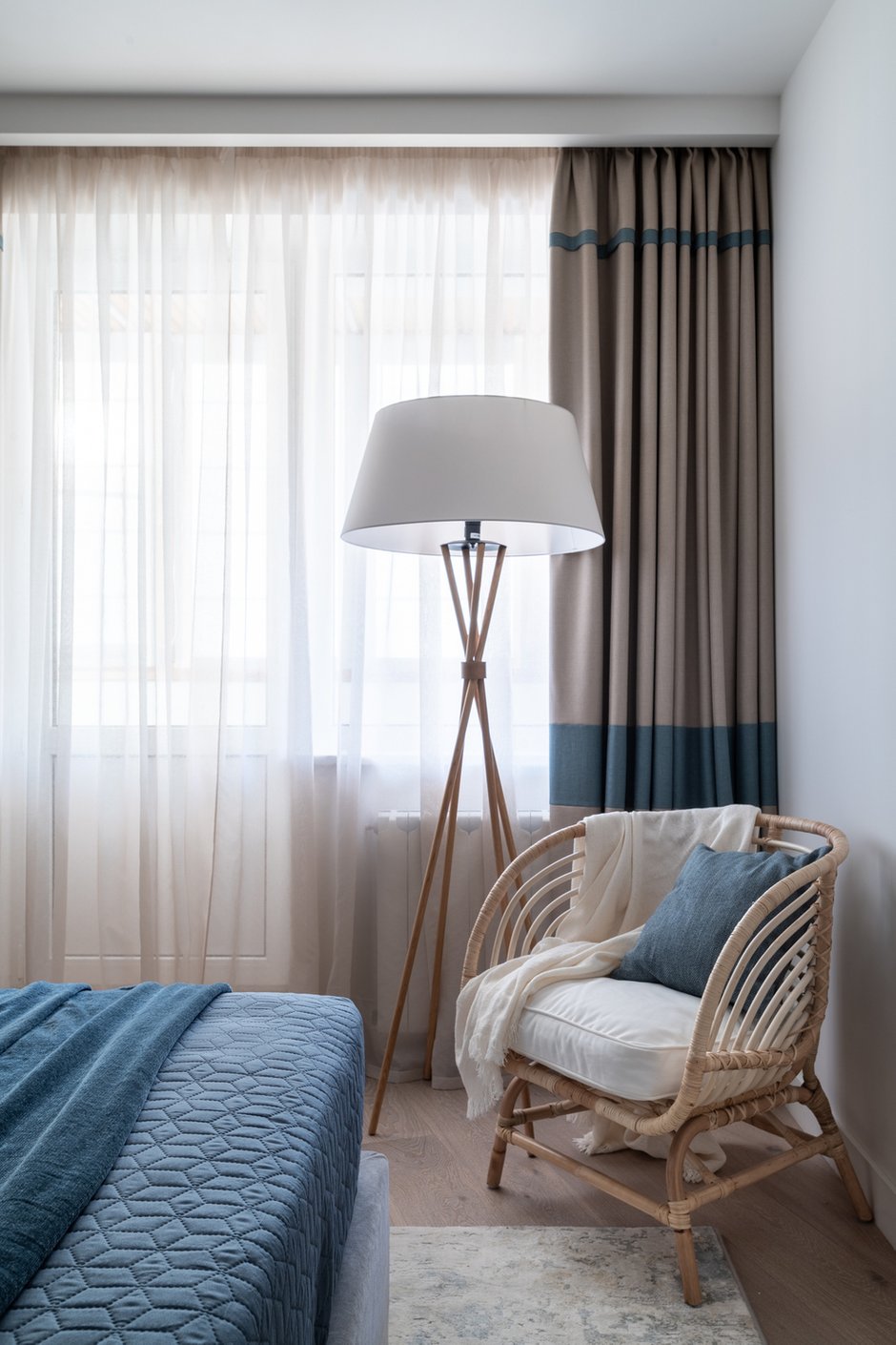 Средиземноморские нотки в спальне поддержали голубыми полосами на шторах и текстилем на кровати. Плетеное кресло из ротанга также отсылает к побережью.