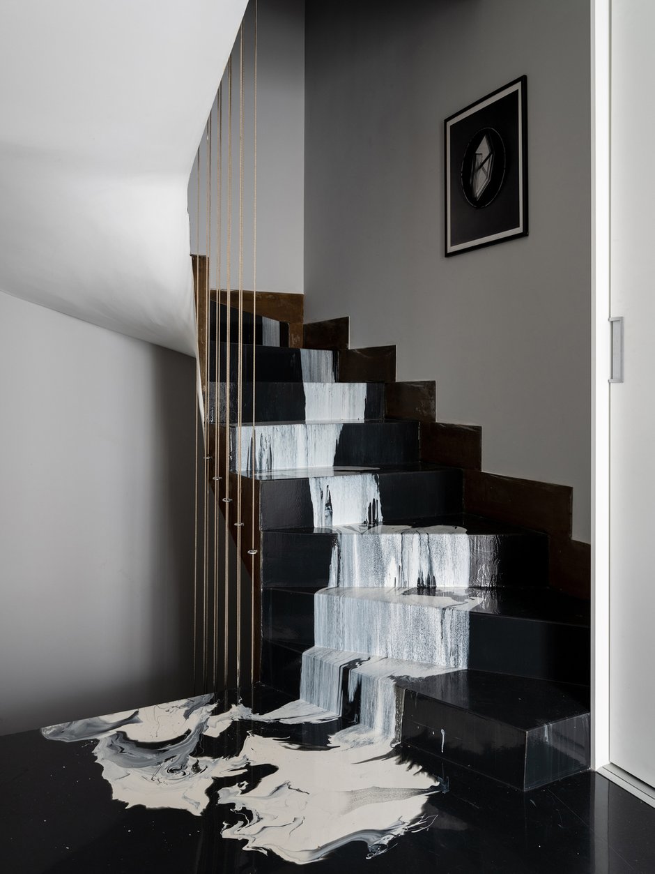 Вторая лестница выполнена из эпоксидной смолы, напоминающей жидкий мрамор. Обе лестницы дополнены ограждениями из металлических тросов, идущими до потолка.